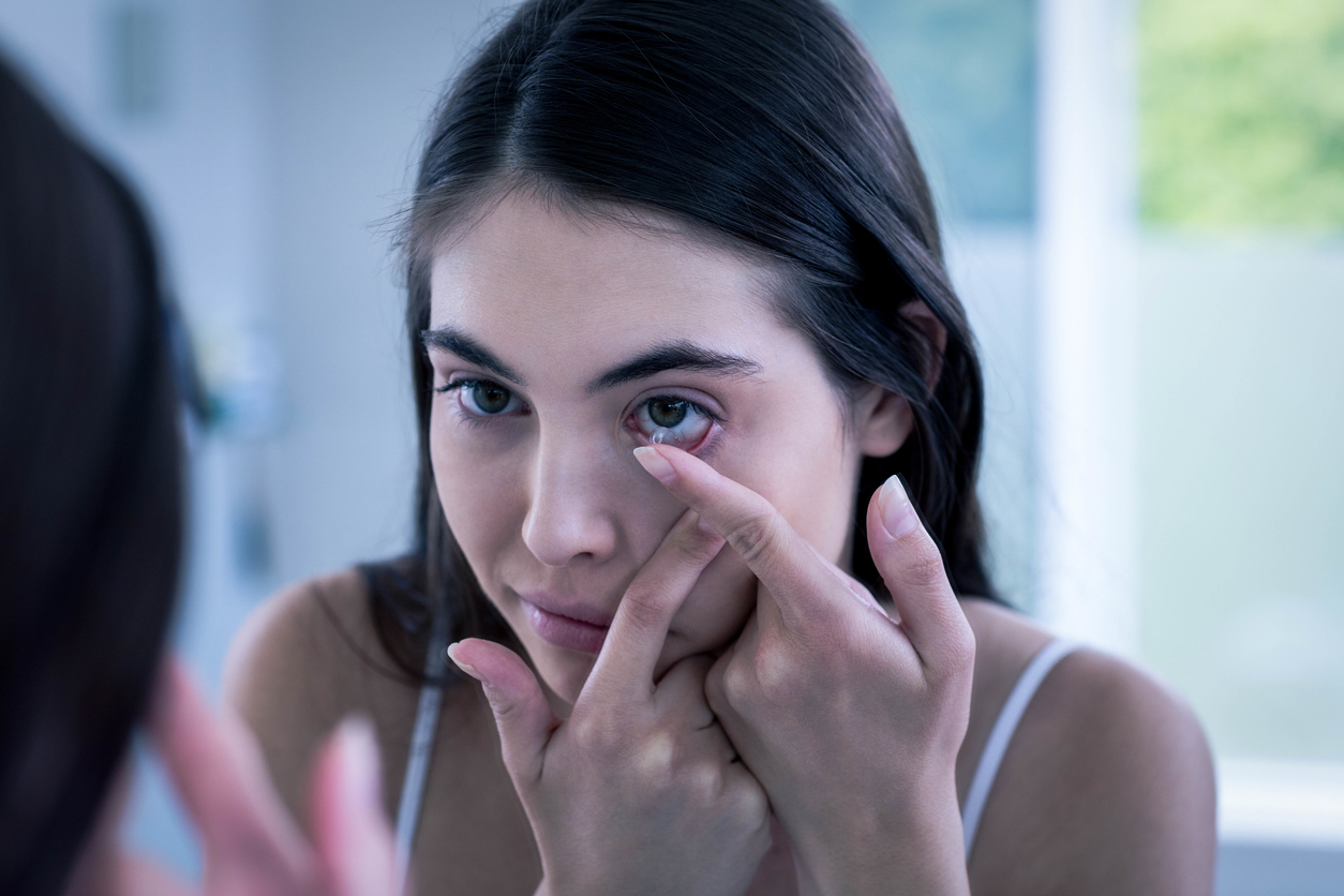 Brunette putting her contact lens in bathroom